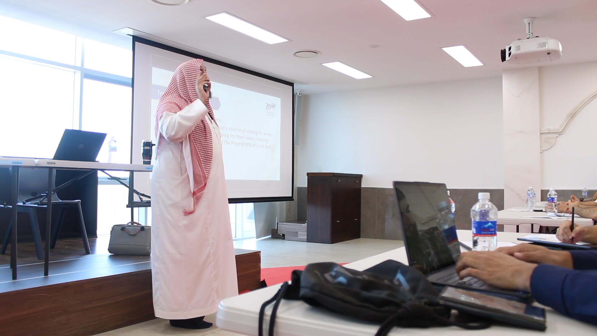 A Shurayh instructor teaching in front of the projector screen